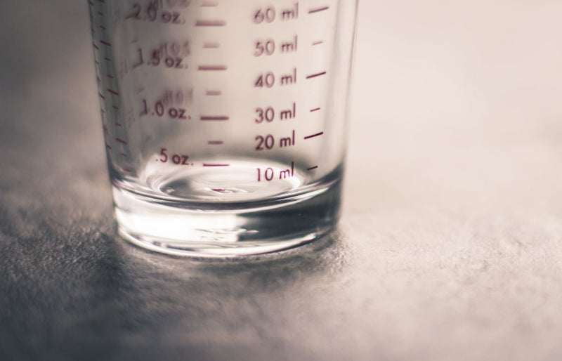 An artistic view of an empty measuring glass highlighting metric and ounce measurements.