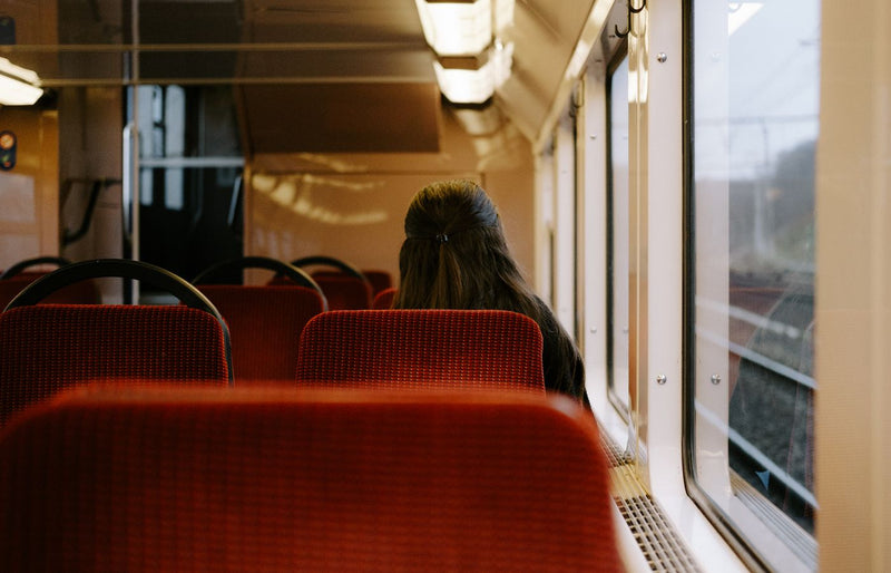 Woman sitting alone on a train, gazing out the window. Capturing solitude and reflection during travel.
