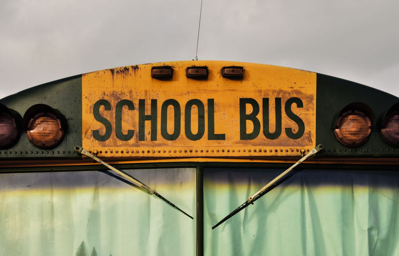 Detailed shot of a classic yellow school bus front with visible window and wipers.