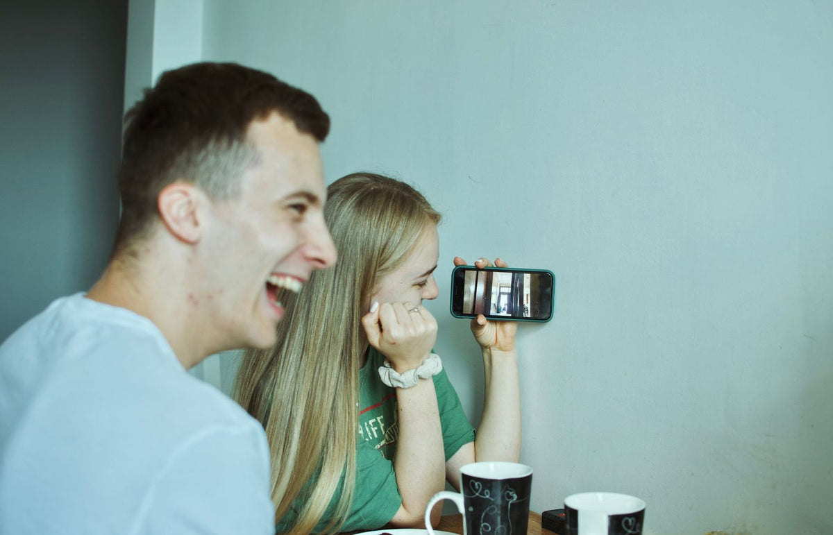 A group of friends laughing and enjoying a video call on a smartphone indoors.