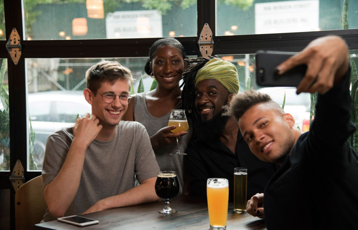 Group of cheerful friends taking a selfie, enjoying drinks at a bar.