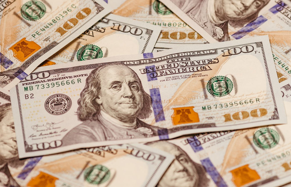Close-up view of multiple US hundred dollar bills showcasing Benjamin Franklin.