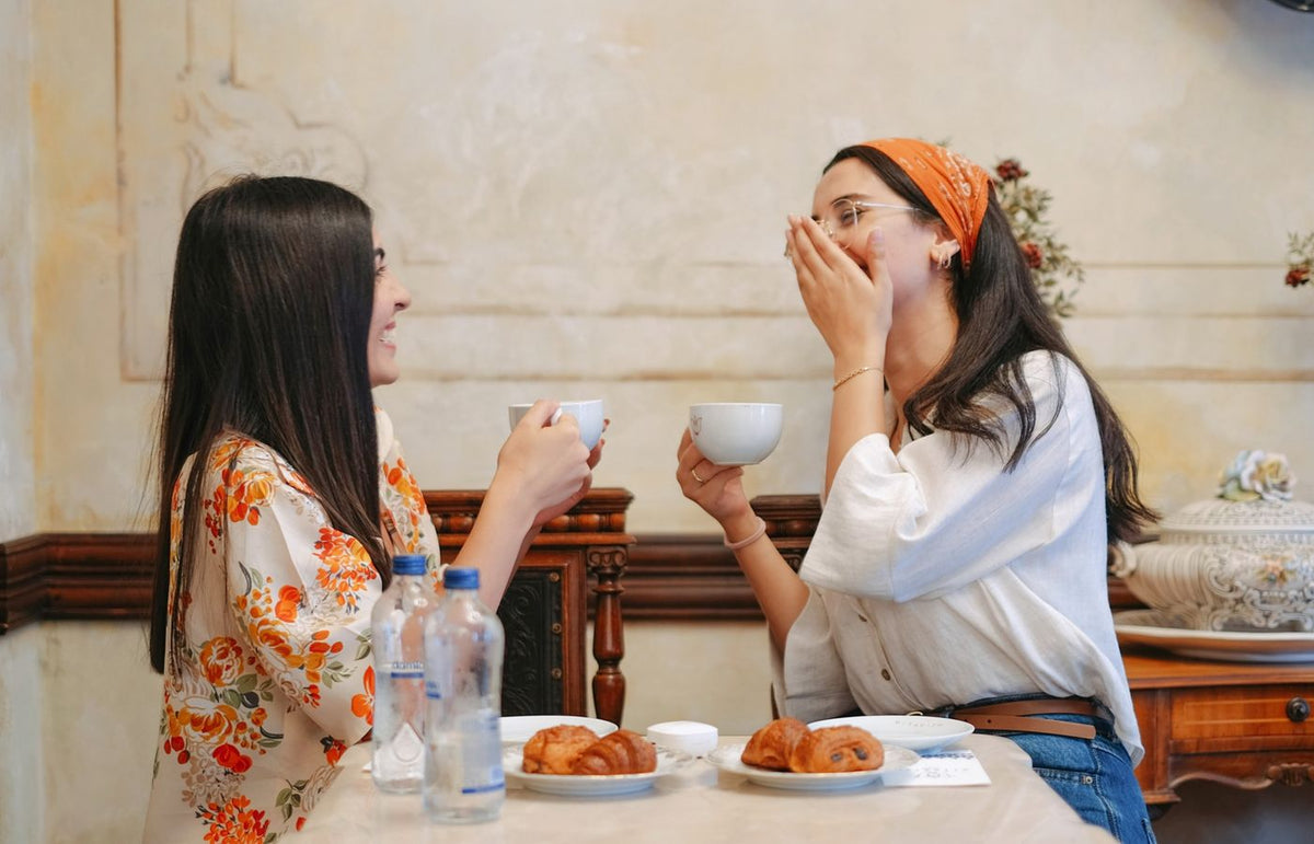 Two women sharing happiness and coffee at a cozy cafe.