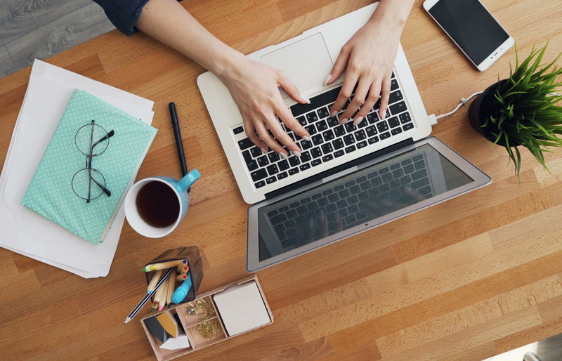 Aerial view of a contemporary desk setup with a laptop, coffee, and accessories, emphasizing productivity.