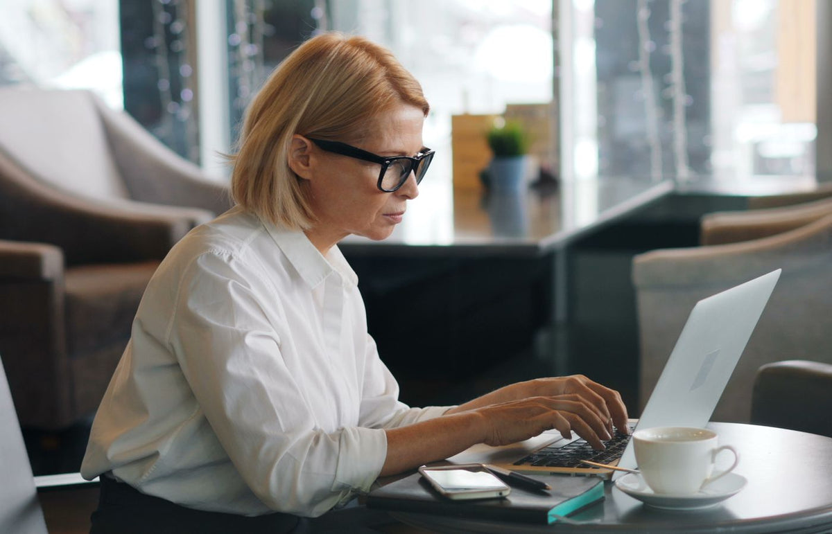 An adult woman using a laptop in a relaxing café environment.