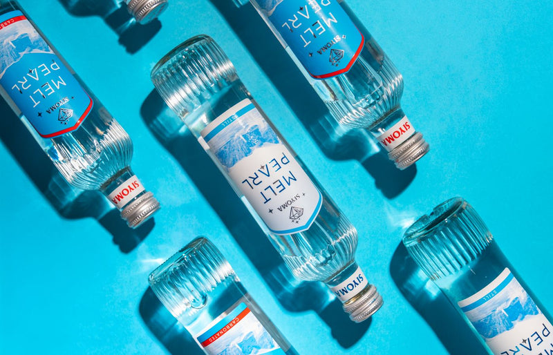 Stylized display of transparent water bottles on a bright blue background, emphasizing freshness.
