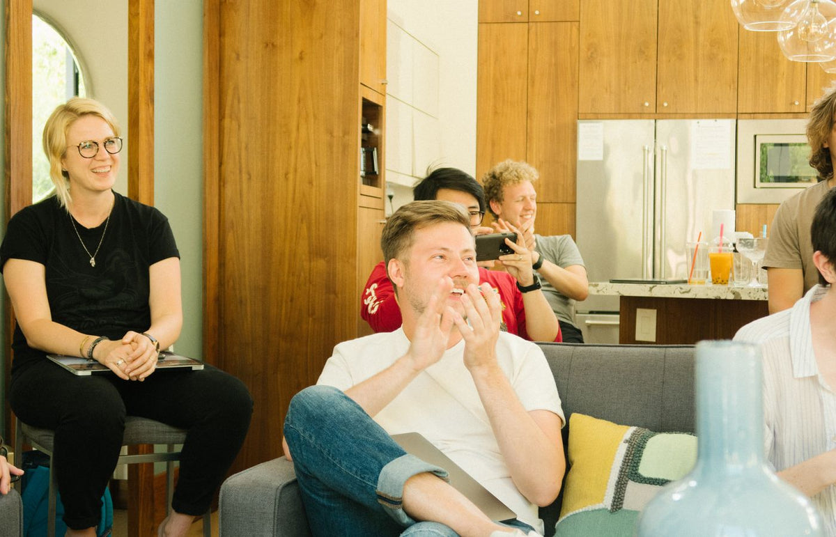 A group of diverse colleagues enjoying a casual meeting indoors with laughter and discussion.