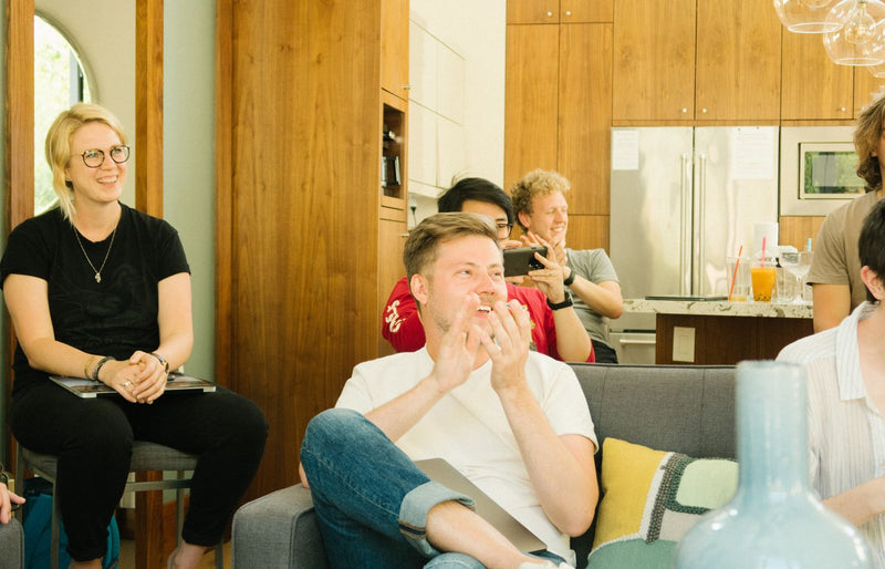 A group of diverse colleagues enjoying a casual meeting indoors with laughter and discussion.