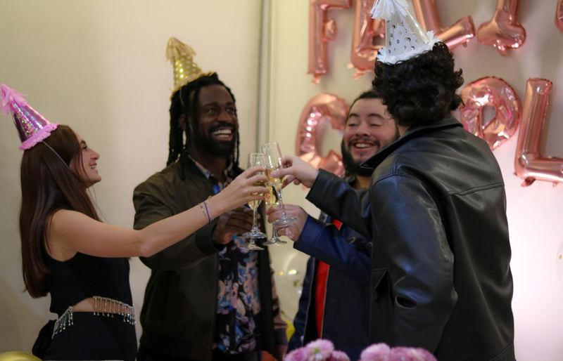 A joyful New Year celebration with friends toasting and wearing party hats indoors.