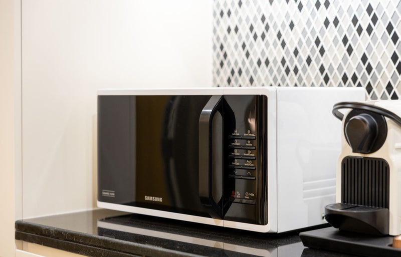 Stylish kitchen setup featuring a black microwave and coffee maker on a counter.