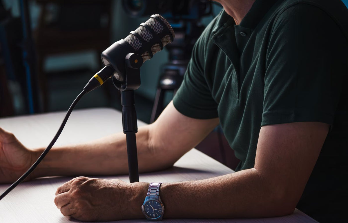 Close-up of a person recording a podcast in a studio, featuring a microphone and professional audio equipment.