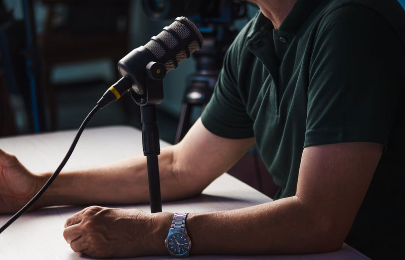 Close-up of a person recording a podcast in a studio, featuring a microphone and professional audio equipment.