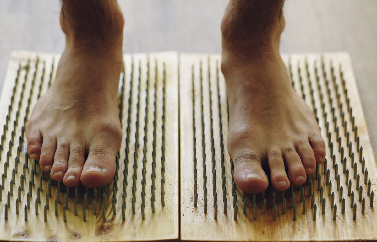Close-up feet on spiked board for massage therapy and health benefits.