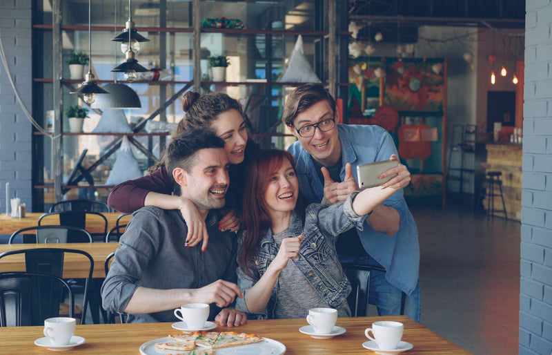 A joyful group of friends capturing a selfie together at a cozy café table.