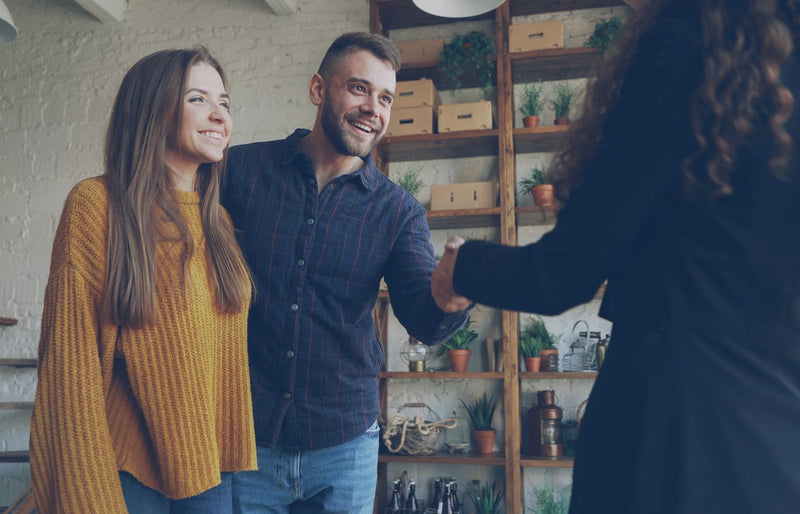 Smiling couple meets with real estate agent in a stylish indoor setting.