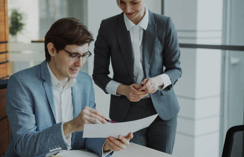 Two business professionals discussing a document in a modern office setting.