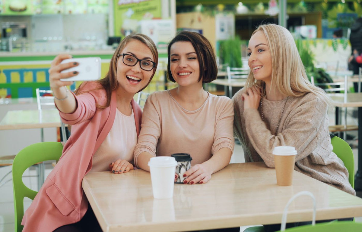 Three friends capturing a joyful moment with a selfie in a trendy cafe.