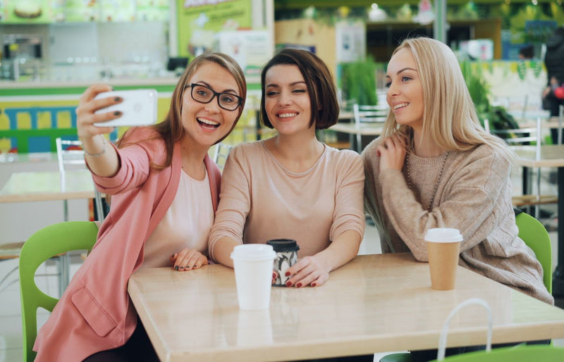 Three friends capturing a joyful moment with a selfie in a trendy cafe.