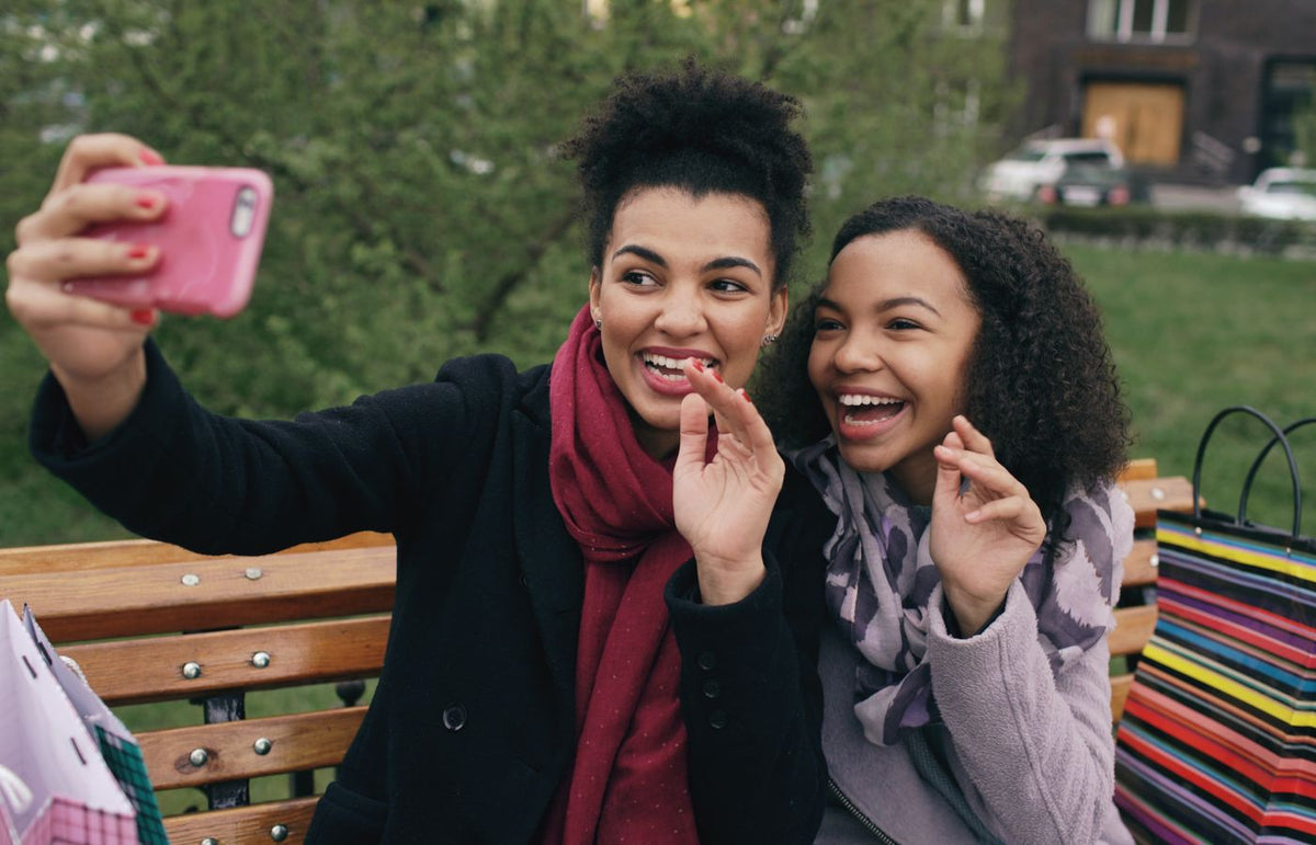 Two friends capturing memories with a selfie on a sunny day in the park.