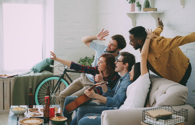 Group of friends hanging out indoors, playing guitar, and having fun together.