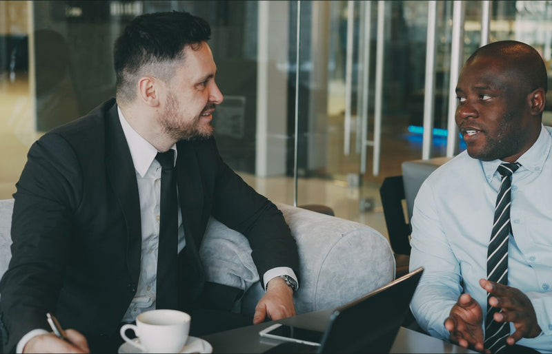 Two businessmen having a discussion in a modern cafe setting.