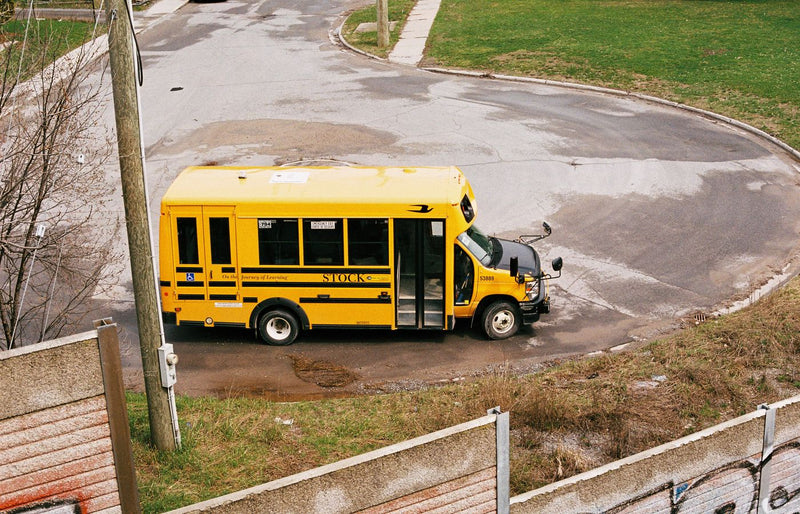 A yellow school bus navigates a suburban roundabout on a clear day, showcasing urban transportation.