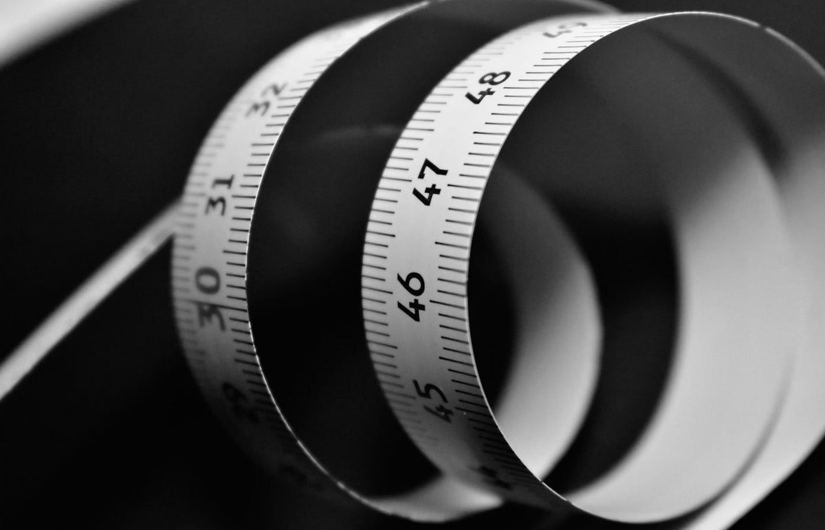 Artistic black and white photo of a coiled measuring tape with visible length markings.