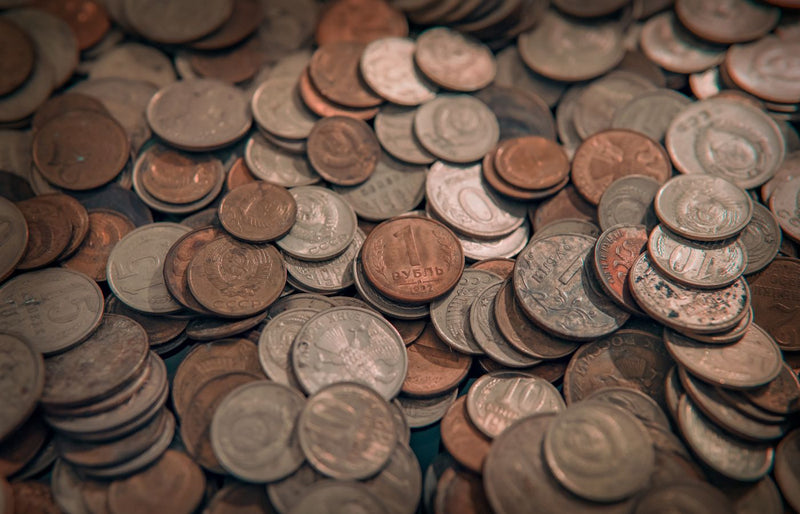 A scattered collection of various vintage coins with copper and silver tones, depicting wealth and currency.