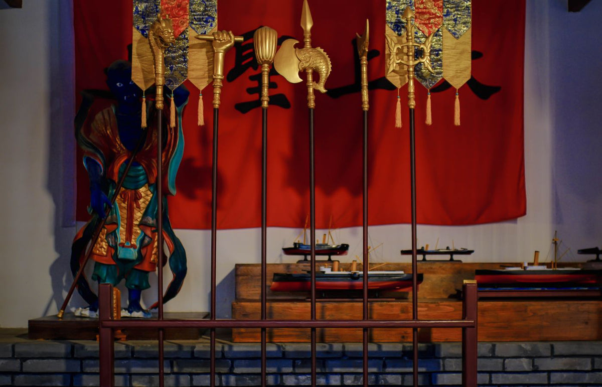 Statue of a samurai with ceremonial flags in a traditional Japanese setting.