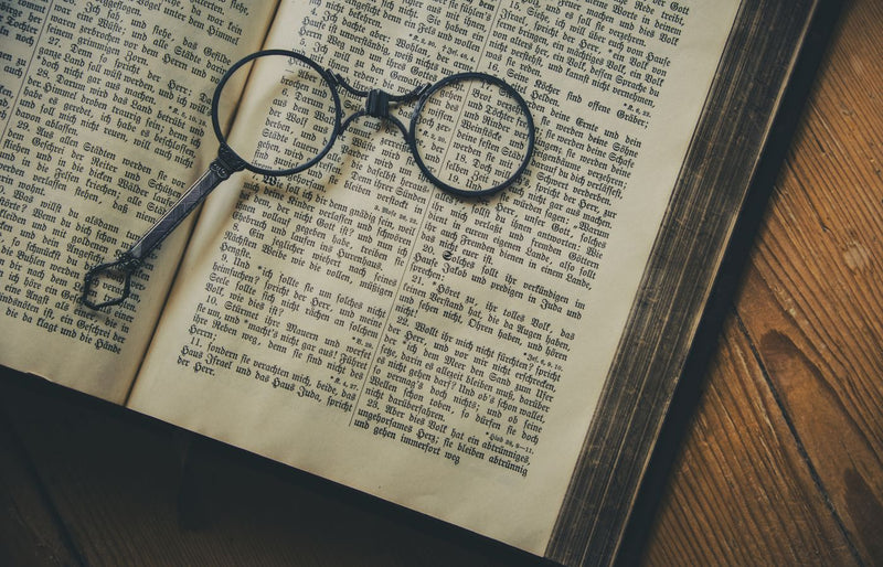A vintage book with old-fashioned spectacles resting on its pages, symbolizing knowledge and history.