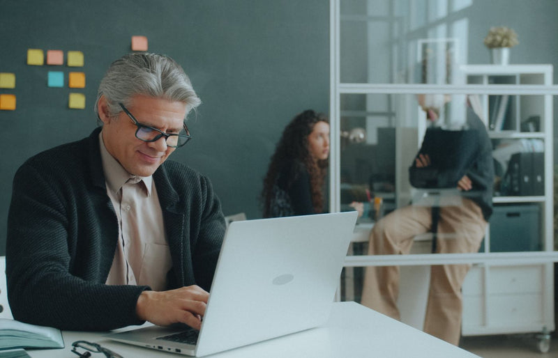 Mature man working on a laptop in an office, capturing a productive and focused work environment.
