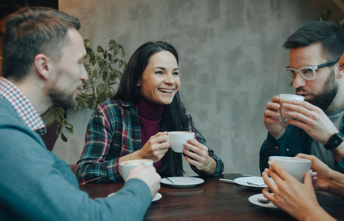 A diverse group of young adults having a lively coffee chat indoors.