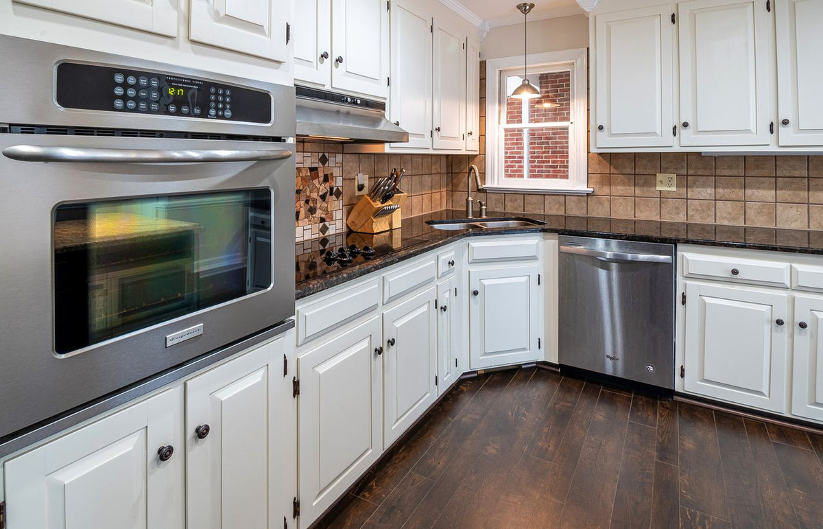 Spacious kitchen featuring white cabinets, stainless steel appliances, and wooden flooring.