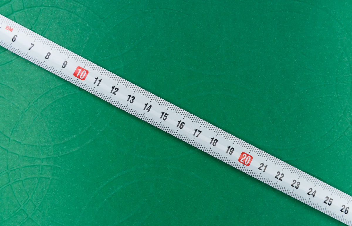 A close-up shot of a tape measure on a textured green background, showing precise measurements.