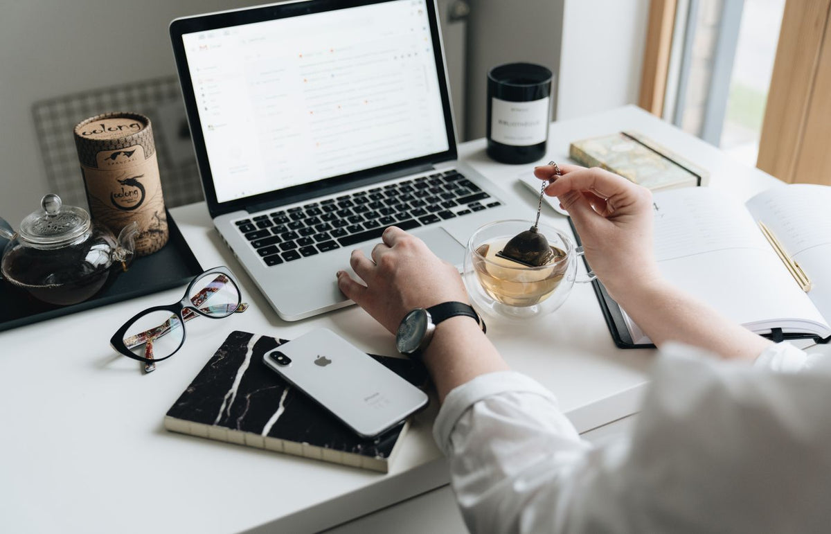 A cozy home office scene with a laptop, tea, and workspace essentials.