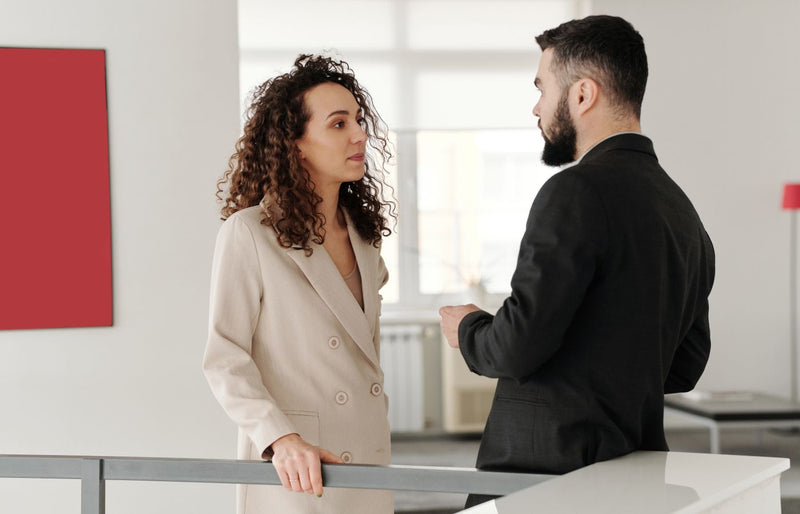 Two professionals engaged in a discussion in a bright, modern office setting.