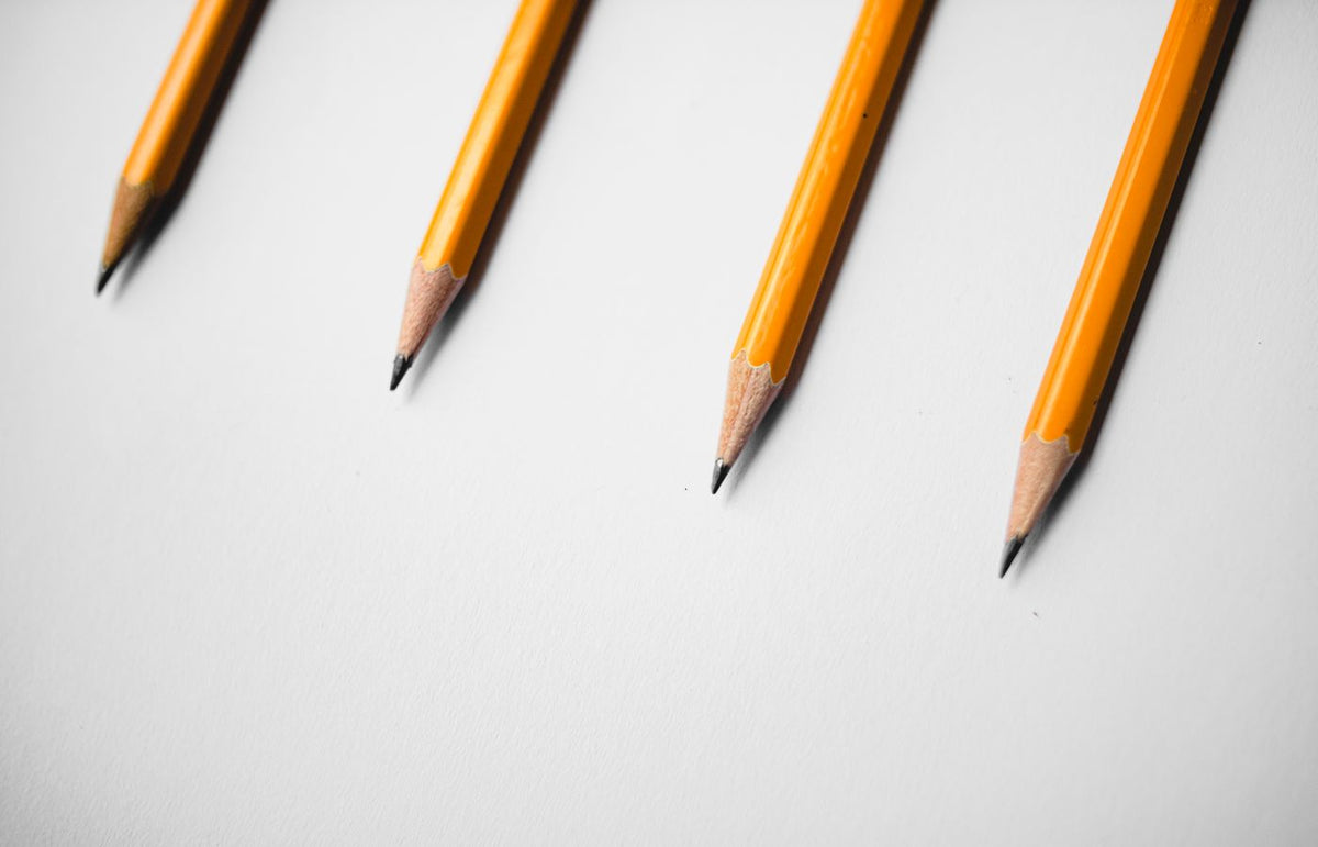 Minimalist image of four yellow pencils arranged diagonally on a white background.