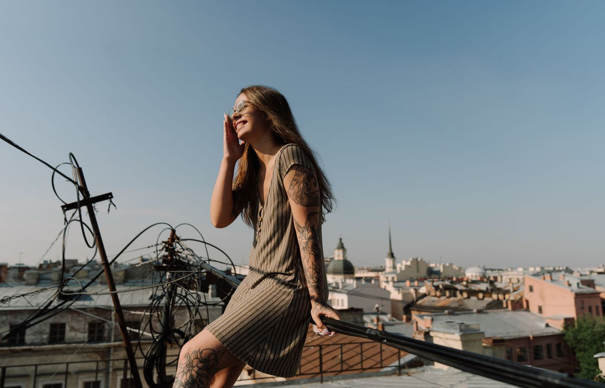 A young woman enjoys a summer day on a rooftop overlooking a cityscape.