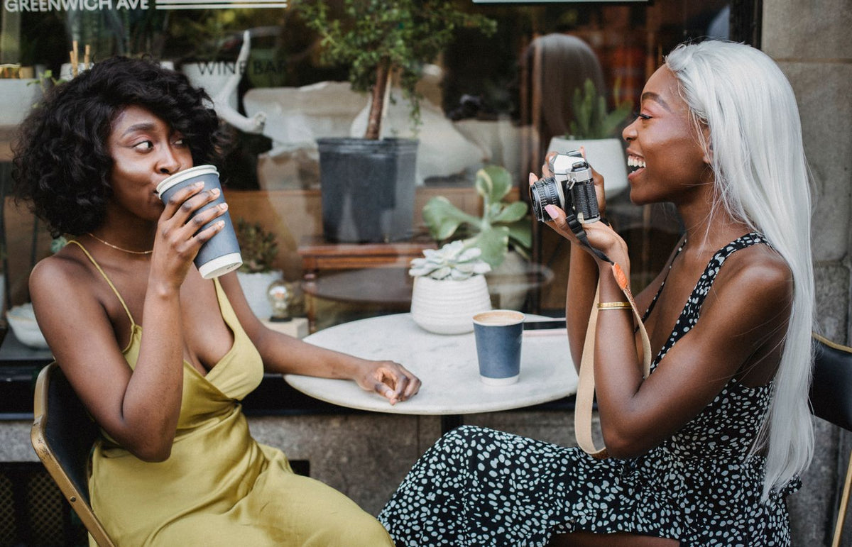 Two women enjoying coffee and photography at a cafe. Relaxed atmosphere and friendship captured outdoors.