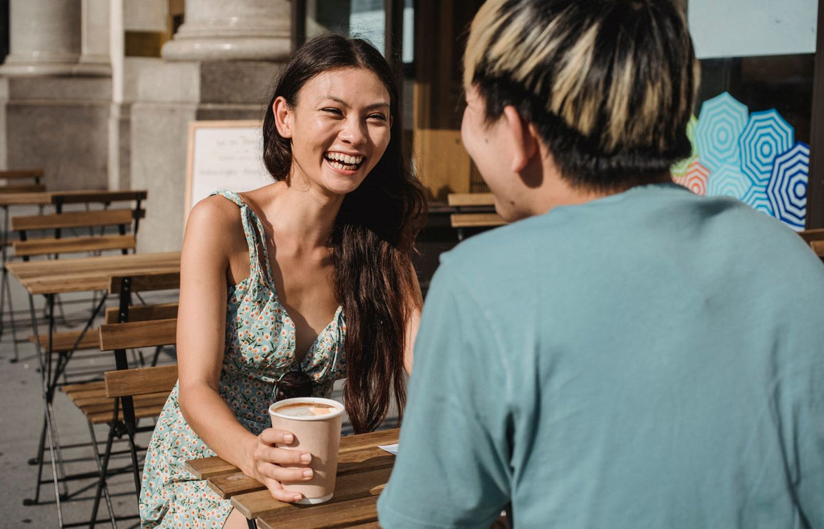 Two friends enjoying a sunny day, chatting over coffee at an outdoor cafe.