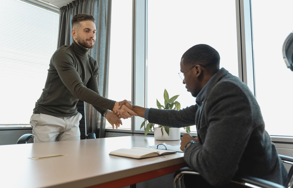 Two businessmen shaking hands in a modern office after a successful meeting or interview.