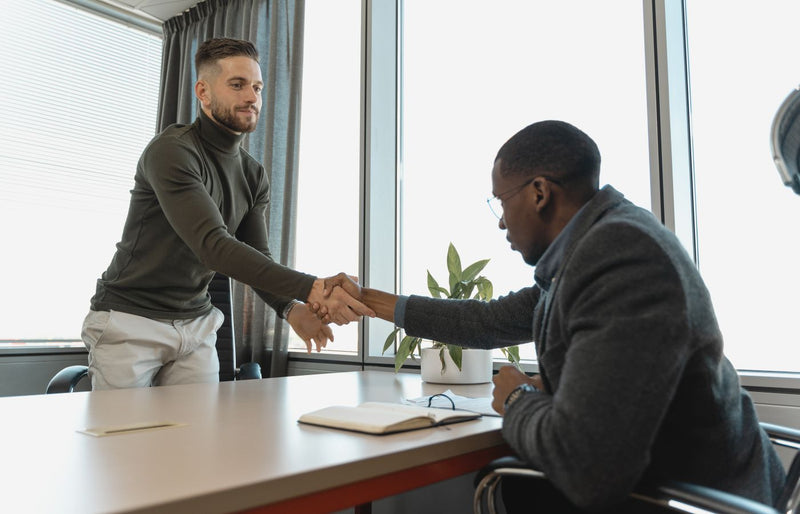 Two businessmen shaking hands in a modern office after a successful meeting or interview.