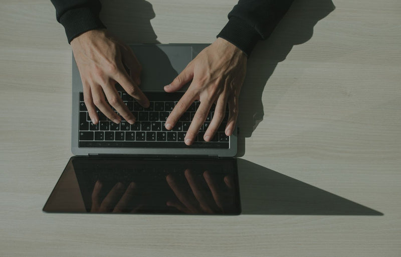 Overhead shot of hands typing on a laptop, showcasing technology and internet usage.