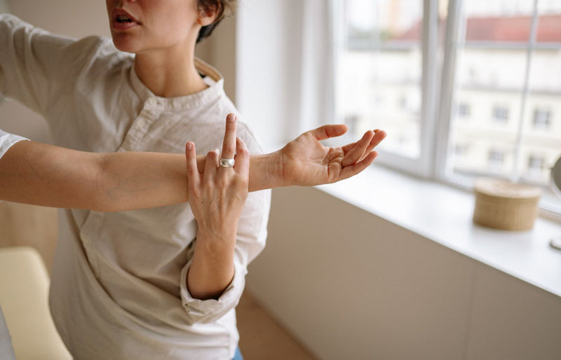 Physical therapist stretches a woman's arm in a sunny room.