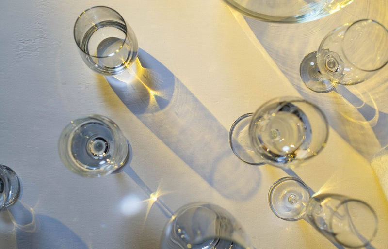Crystal glasses on a table casting intricate shadows in sunlight, creating an artistic effect.