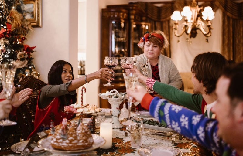A joyful family gathering around a Christmas dinner table, toasting and celebrating together.