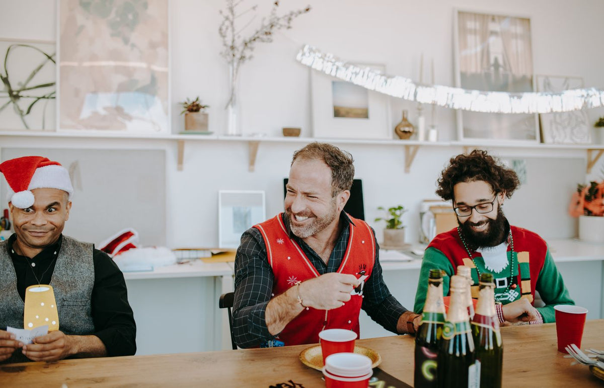 Group of friends enjoying a festive gathering with drinks and laughter indoors.