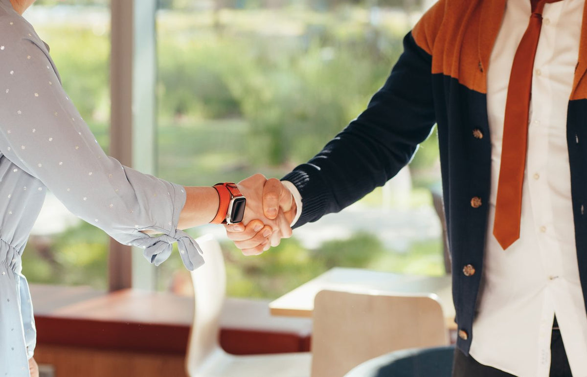 Close-up of colleagues shaking hands in an office, symbolizing teamwork and collaboration.