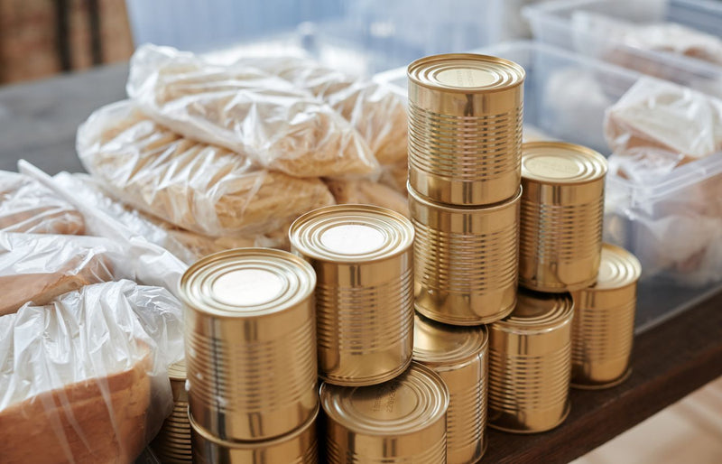 A stack of canned goods and packaged foods on a table, perfect for donation drives.