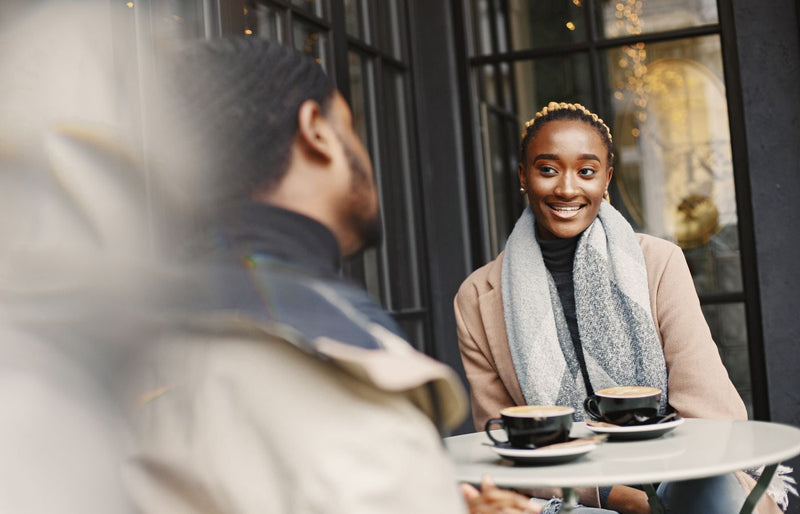 A joyful woman engaging in conversation at a stylish outdoor café setting.